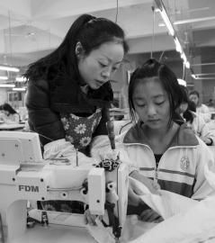 大英縣中等職業技術學校內，企業服裝技師正指導學生進行縫紉操作。